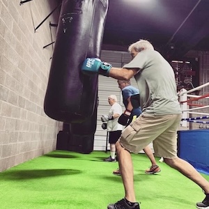 Group boxing class hitting the heavy bag.